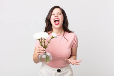 Güzel bir kadın kızgın, sinirli ve hayal kırıklığına uğramış görünüyor ve elinde dekoratif bir saksı tutuyor.