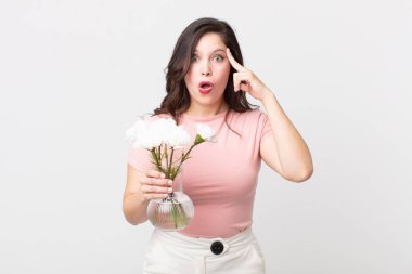 Güzel kadın şaşırmış görünüyor, yeni bir düşünce, fikir ya da konsept fark ediyor ve elinde dekoratif bir saksı tutuyor.