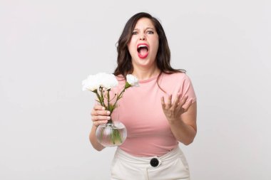 Güzel bir kadın umutsuz görünüyor, hayal kırıklığına uğramış ve stresli ve elinde dekoratif bir saksı tutuyor.