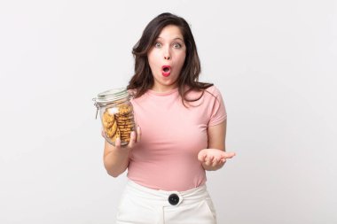 Güzel bir kadın şok olmuş ve şaşırmış hissediyor ve elinde bir kurabiye şişesi tutuyor.