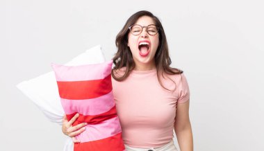 Güzel bir kadın agresif bir şekilde bağırıyor, pijama giyiyor ve yastık tutuyor.