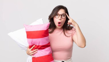 Güzel kadın şaşırmış görünüyor, yeni bir düşünce, fikir ya da konsept fark ediyor pijama giyiyor ve yastık tutuyor.