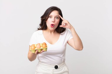 Güzel kadın şaşırmış görünüyor, yeni bir düşünce, fikir ya da konsept fark ediyor ve elinde bir yumurta kutusu tutuyor.