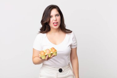 Güzel bir kadın kafası karışmış, kafası karışmış ve elinde bir yumurta kutusu tutuyor.