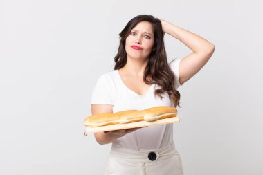 Güzel bir kadın kendini stresli, endişeli ya da korkmuş hissediyor. Elleri başının üstünde ve elinde ekmek tepsisi tutuyor.