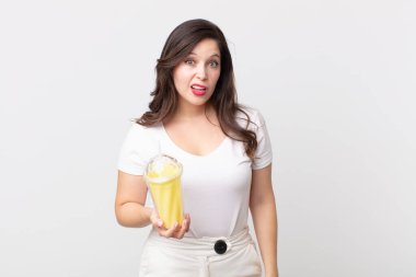 Güzel bir kadın şaşkın ve şaşkın hissediyor ve elinde vanilyalı milkshake tutuyor.