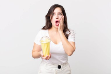 Güzel bir kadın şoke olmuş, korkmuş ve elinde vanilyalı milkshake tutuyor.
