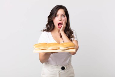 Güzel bir kadın şok olmuş ve korkmuş hissediyor ve elinde ekmek tepsisi tutuyor.