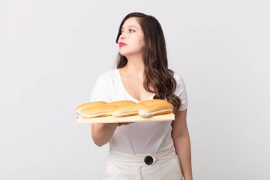 Profilde güzel bir kadın hayal ediyor, hayal ediyor ve elinde bir ekmek tepsisi tutuyor.