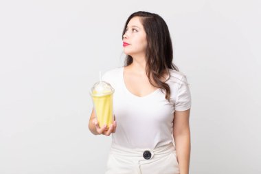 Profilde güzel bir kadın hayal ediyor, hayal ediyor ya da hayal ediyor ve elinde vanilyalı milkshake tutuyor.