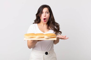 Güzel bir kadın son derece şaşkın ve şaşırmış hissediyor ve elinde ekmek tepsisi tutuyor.