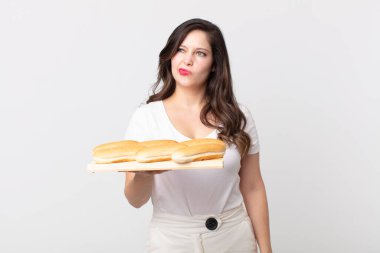 Güzel bir kadın üzgün, üzgün ya da kızgın ve yana bakıyor ve elinde ekmek tepsisi tutuyor.