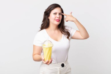 Güzel bir kadın şaşkın ve şaşkın hissediyor, deli olduğunu ve elinde vanilyalı milkshake tuttuğunu gösteriyor.
