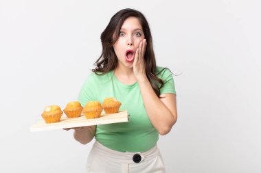 Güzel bir kadın şok olmuş, korkmuş ve elinde kek tepsisi tutuyormuş.