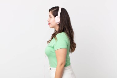 Profil görünümlü güzel bir kadın kulaklıkla müzik dinliyor, hayal ediyor ya da hayal kuruyor.