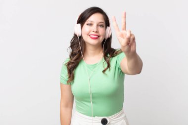 Güzel bir kadın gülümsüyor ve arkadaş canlısı görünüyor. İki numara kulaklıkla müzik dinliyor.