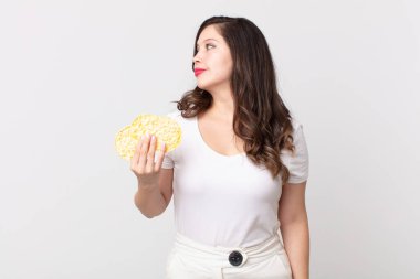 Profilde güzel bir kadın hayal kuruyor, hayal ediyor ve elinde diyet pirinç keki tutuyor.