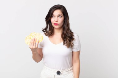 Güzel bir kadın üzgün, üzgün ya da kızgın ve diyet pirinç keki tutuyor.