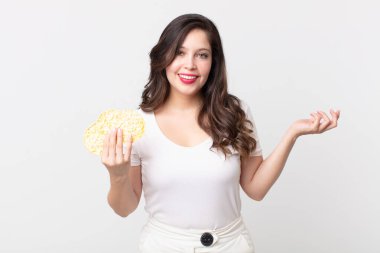 Güzel bir kadın kendini mutlu hisseder, bir çözüm ya da fikir bulduğunda şaşırır ve elinde diyet pirinç keki tutar.