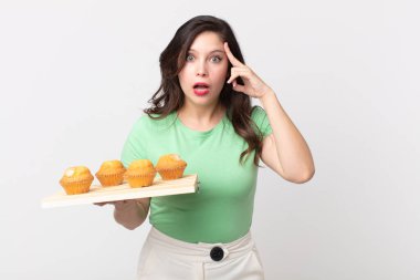 Güzel kadın şaşırmış görünüyor, yeni bir düşünce, fikir ya da konsept fark ediyor ve elinde kek tepsisi tutuyor.