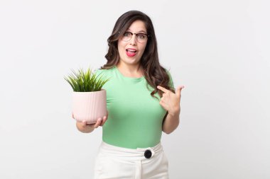 Güzel bir kadın kendini mutlu hissediyor ve heyecanlı ve elinde dekoratif bir bitkiyle kendini gösteriyor.