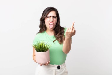 Güzel bir kadın kızgın, sinirli, asi ve agresif hissediyor ve elinde dekoratif bir bitki tutuyor.