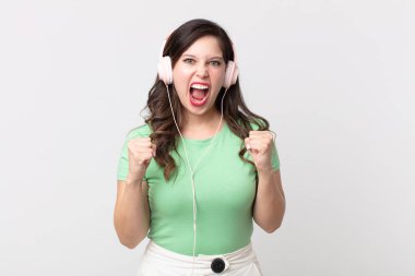 Güzel bir kadın sinirli bir ifadeyle bağırıyor kulaklıkla müzik dinliyor.