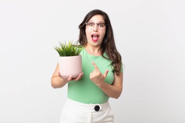 Güzel bir kadın heyecanlı ve şaşırmış görünüyor. Tarafını gösteriyor ve elinde dekoratif bir bitki tutuyor.