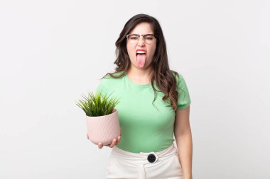 Güzel bir kadın midesi bulanmış ve rahatsız olmuş hissediyor. Dilini çıkarmış ve elinde dekoratif bir bitki tutuyor.