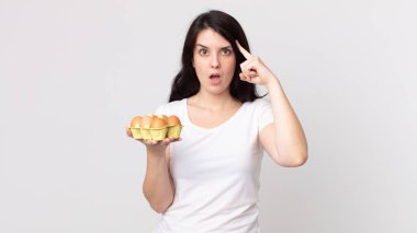 Güzel kadın şaşırmış görünüyor, yeni bir düşünce, fikir ya da konsept fark ediyor ve elinde bir yumurta kutusu tutuyor.