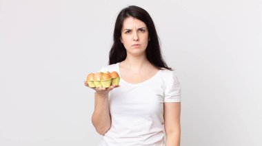 Güzel bir kadın üzgün, üzgün ya da kızgın hissediyor ve yan tarafa bakıyor ve elinde bir yumurta kutusu tutuyor.
