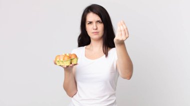 Güzel bir kadın kapiş ya da para hareketi yapıp, sana ödemeni ve yumurta kutusu tutmanı söylüyor.