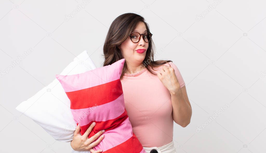 pretty woman looking arrogant, successful, positive and proud wearing pajamas and holding a pillow