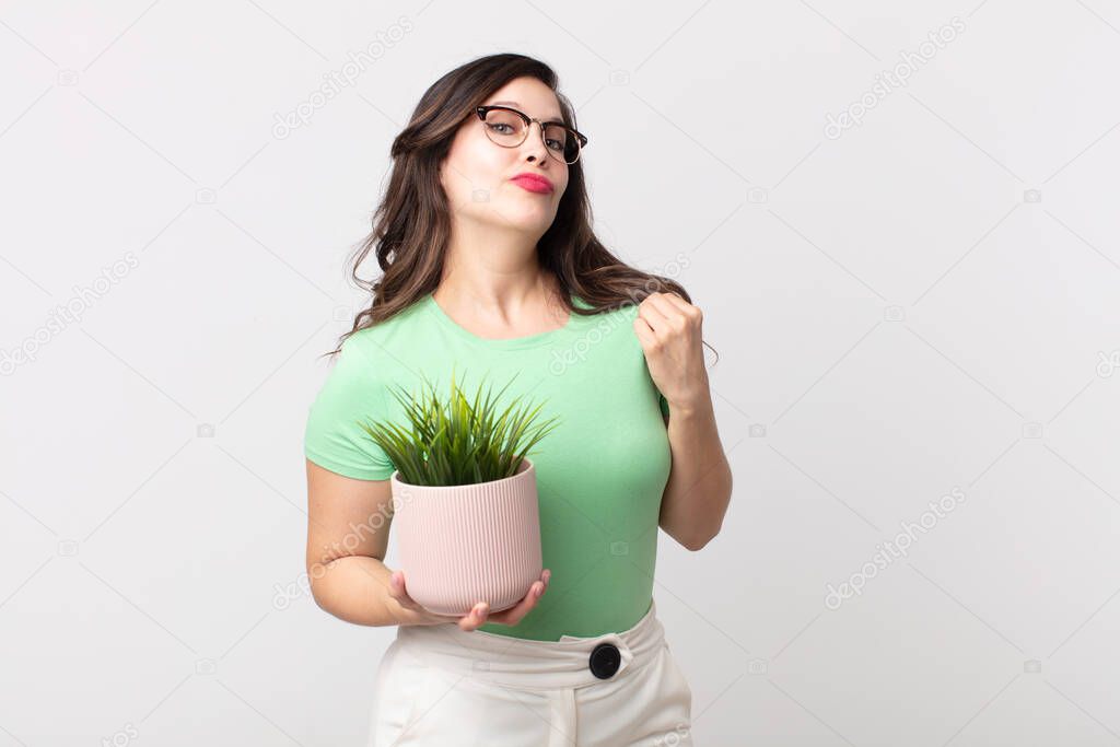 pretty woman looking arrogant, successful, positive and proud and holding a decorative plant