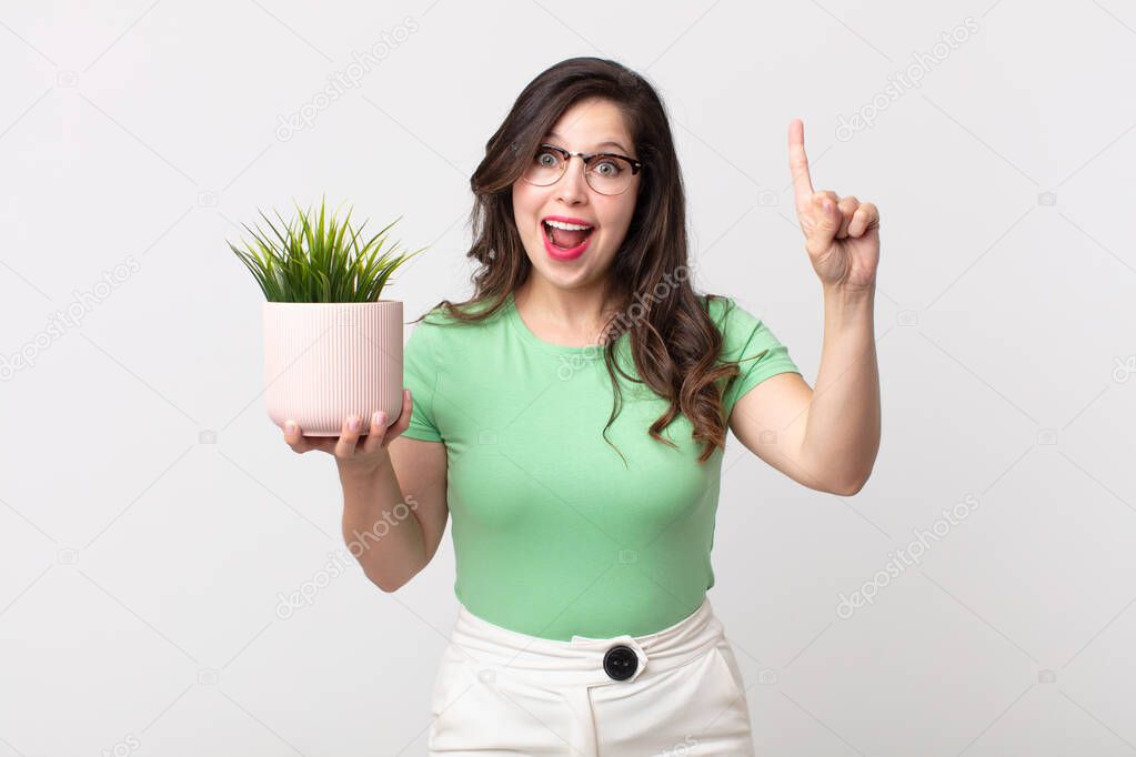 pretty woman feeling like a happy and excited genius after realizing an idea and holding a decorative plant