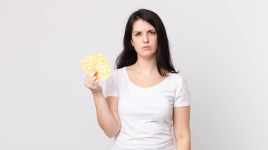 Güzel bir kadın üzgün, üzgün ya da kızgın ve diyet pirinç keki tutuyor.