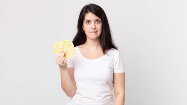 Kafası karışmış ve diyet pirinç keki tutan güzel bir kadın.