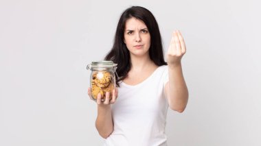 Güzel bir kadın kapiş ya da para hareketi yapıyor, sana ödemeni söylüyor ve elinde cam bir kurabiye şişesi tutuyor.