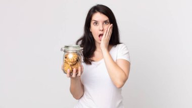 Güzel kadın şok olmuş ve korkmuş hissediyor ve elinde cam bir kurabiye şişesi tutuyor.