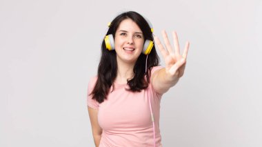 Güzel bir kadın gülümsüyor ve arkadaş canlısı görünüyor. Dört numara kulaklıkla müzik dinliyor.