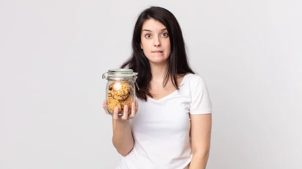 Mujer Bonita Buscando Desconcertado Confundido Sosteniendo Una Botella Vidrio Galletas —  Fotos de Stock