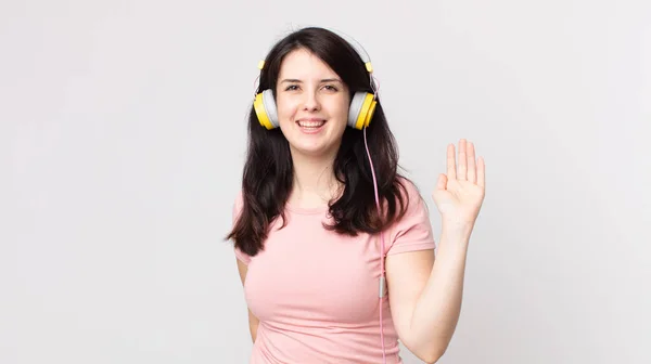 女性は喜んで手を振って歓迎し挨拶するヘッドフォンで音楽を聴く — ストック写真