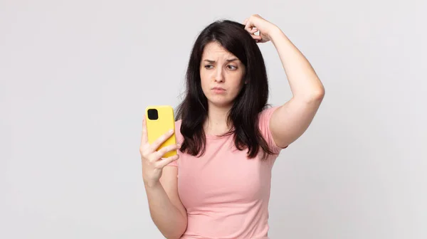 Mujer Bonita Sintiéndose Perpleja Confundida Arañando Cabeza Usando Teléfono Inteligente —  Fotos de Stock