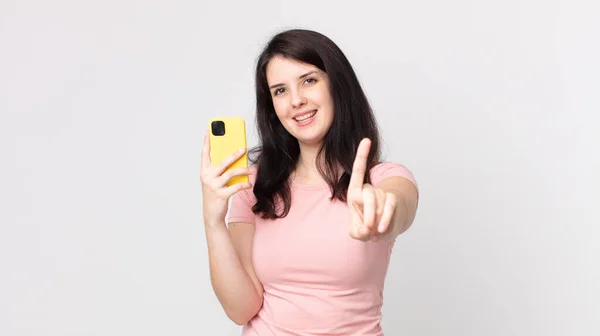 Bonita Mujer Sonriendo Orgullosa Confiadamente Haciendo Número Uno Usando Teléfono — Foto de Stock