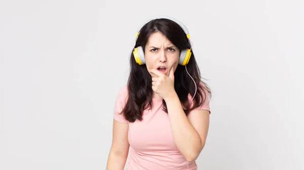 Ładna Kobieta Szeroko Otwartymi Oczami Ręką Podbródku Słuchanie Muzyki Słuchawkami — Zdjęcie stockowe