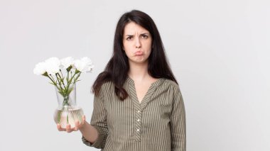 Güzel bir kadın üzgün ve mızmız, mutsuz bir bakışla ağlıyor ve elinde dekoratif bir çiçek tutuyor. Kulaklıklı bir yardımcı ajan.