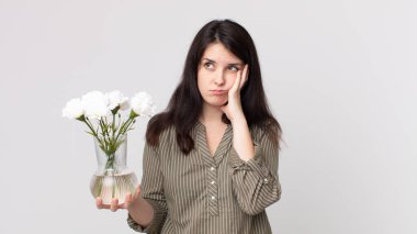 Güzel bir kadın sıkılmış, hayal kırıklığına uğramış ve uykulu hissediyor. Yorucu bir günün ardından elinde dekoratif bir çiçek tutuyor. Kulaklıklı bir yardımcı ajan.