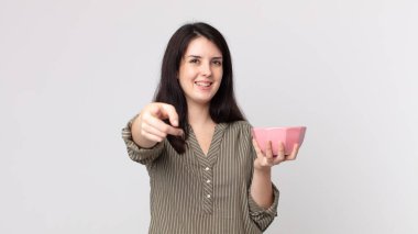 Güzel bir kadın kamerayı işaret ederek boş bir tencere tutarak seni seçiyor. Kulaklıklı bir yardımcı ajan.