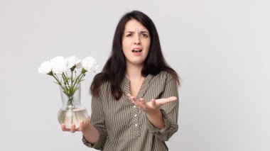 Güzel bir kadın umutsuz, hayal kırıklığına uğramış ve stresli görünüyor ve elinde dekoratif bir çiçek tutuyor. Kulaklıklı bir yardımcı ajan.