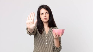 Güzel bir kadın avuçlarını açıp boş bir tencere tutmaktan vazgeçiyor. Kulaklıklı bir yardımcı ajan.